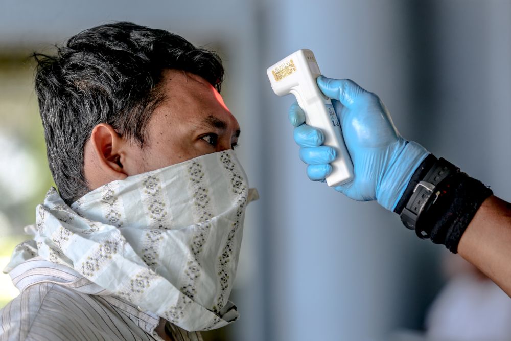 A Giant hypermarket staff screens members of the public on day nine of the movement control order in Kuala Lumpur March 26, 2020. u00e2u20acu201d Picture by Firdaus Latif