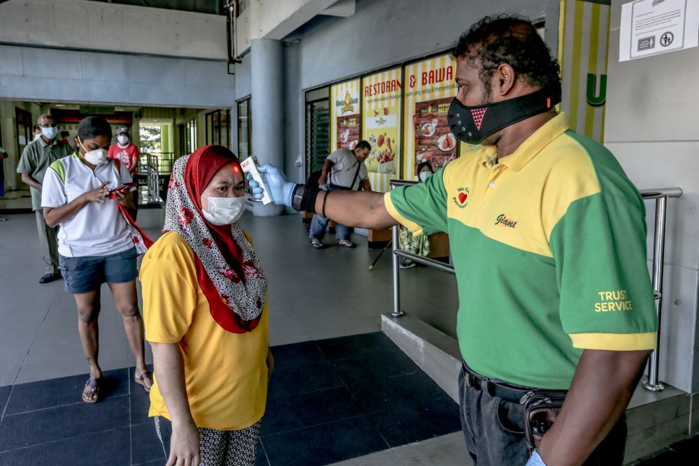 A Giant hypermarket staff screens members of the public on day nine of the movement control order in Kuala Lumpur March 26, 2020. u00e2u20acu201d Picture by Firdaus Latif