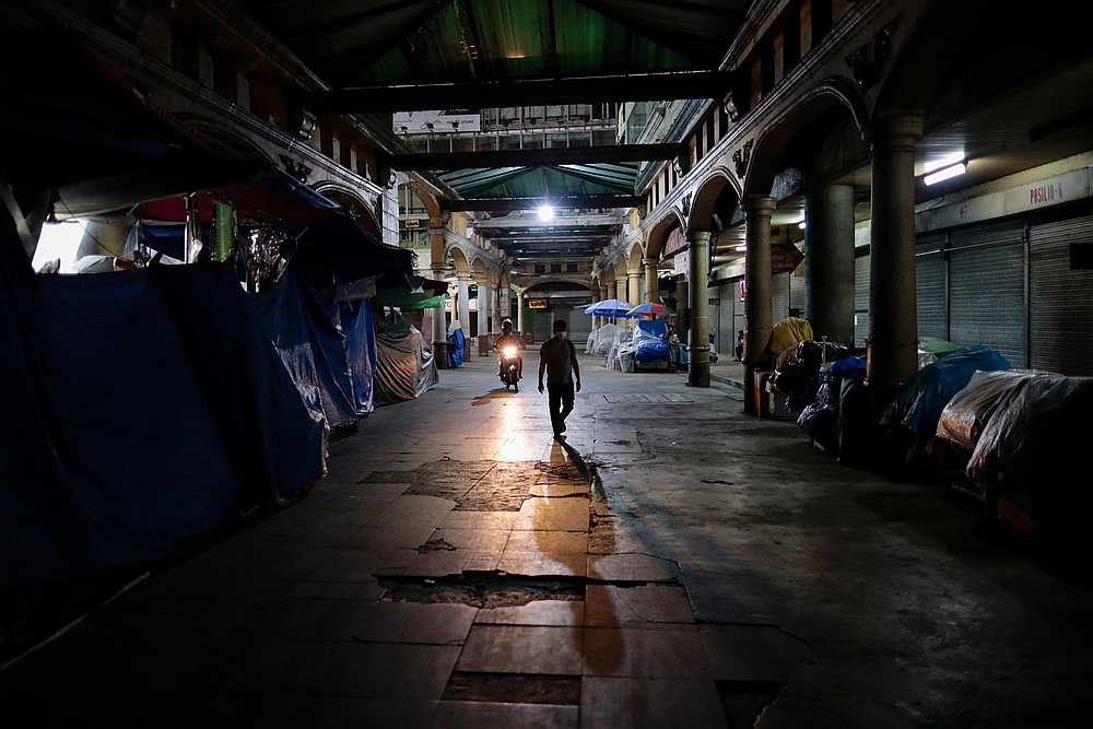 A man wearing a protective mask walks past closed shops in an empty public square following the lockdown in Manila, Philippines March 24, 2020. u00e2u20acu201d Reuters pic