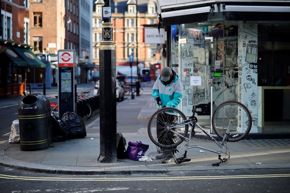 A man wears a mask as he fixes his bicycle in a near deserted London on March 25, 2020, after Britainu00e2u20acu2122s government ordered a lockdown to slow the spread of the novel coronavirus. u00e2u20acu201d AFP pic