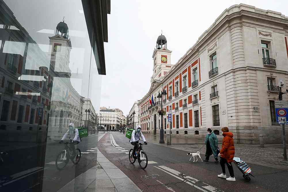 People wearing protective face masks are seen in an almost empty Puerta del Sol, which is a part of a 15-day state of emergency to combat the Covid-19 outbreak in Madrid, Spain March 21, 2020. u00e2u20acu201d Reuters pic