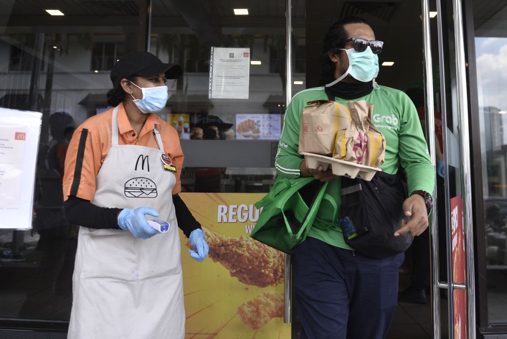 A GrabFood rider picks up his order at a McDonaldu00e2u20acu2122s outlet in Bangsar as the movement control order kicks in on March 18, 2020. u00e2u20acu201d Picture by Miera Zulyana
