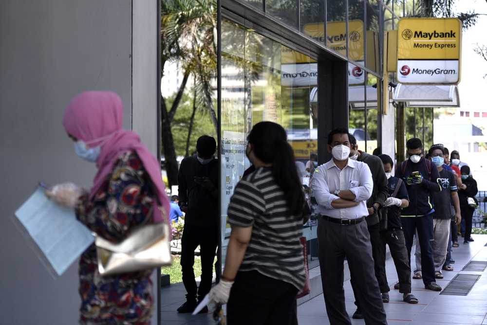 People are seen queuing up outside a Maybank branch in Shah Alam March 26, 2020. ― Picture by Miera Zulyana