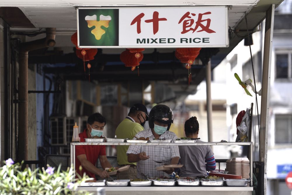 Customers pack food to go at an eatery in Kuala Lumpur March 24, 2020. — Picture by Miera Zulyana