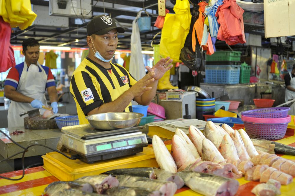 Fishmonger Along, 45, is keeping a positive mindset as people will still need to buy their daily goods like meat, fish, and vegetables. — Picture by Shafwan Zaidon