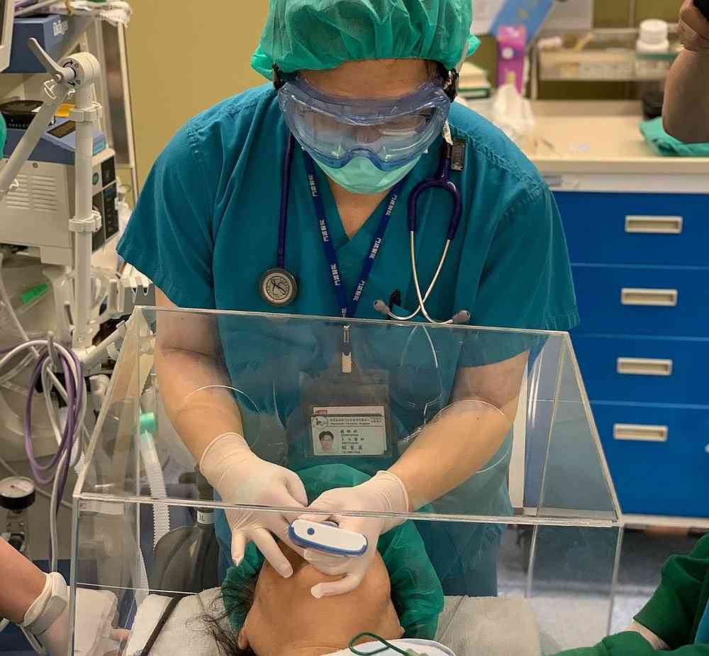A healthcare worker using the PPE box to treat a patient suffering from respiratory failures. u00e2u20acu201d Picture by Dr Lai Hsien Yung 