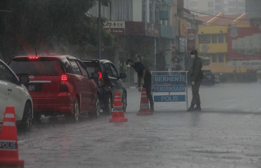 Malaysian Armed Forces and police personnel brave the heavy downpour to man a roadblock on Jalan Sultan Iskandar, Ipoh March 24, 2020. u00e2u20acu201d Picture by Farhan Najib