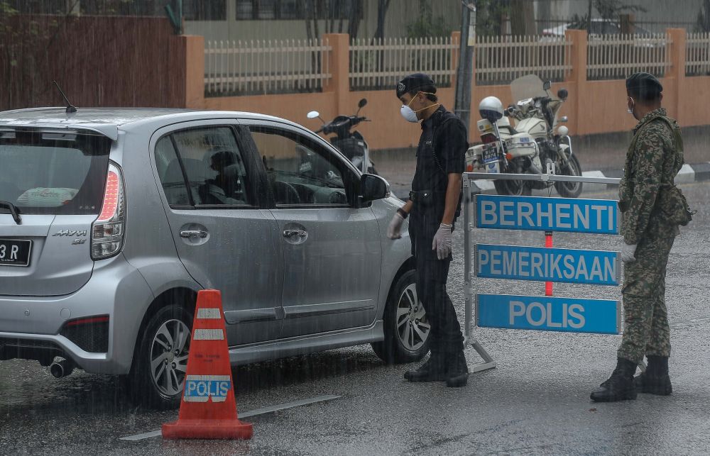 Malaysian Armed Forces and police personnel brave the heavy downpour to man a roadblock on Jalan Sultan Iskandar, Ipoh March 24, 2020. u00e2u20acu201d Picture by Farhan Najib
