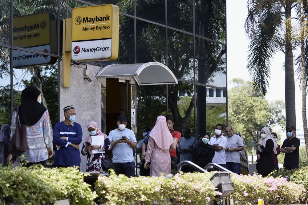 Members of the public observe social distancing guidelines as they queue outside a Maybank branch in Shah Alam March 26, 2020. u00e2u20acu201d Picture by Miera Zulyana