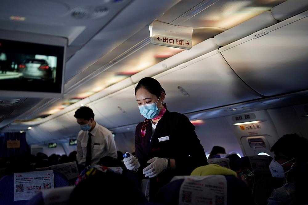 A flight attendant wearing a face mask to prevent Covid-19 takes body temperature measurements of passengers on a Shanghai Airlines flight in Shanghai, China March 25, 2020. u00e2u20acu201d Reuters pic