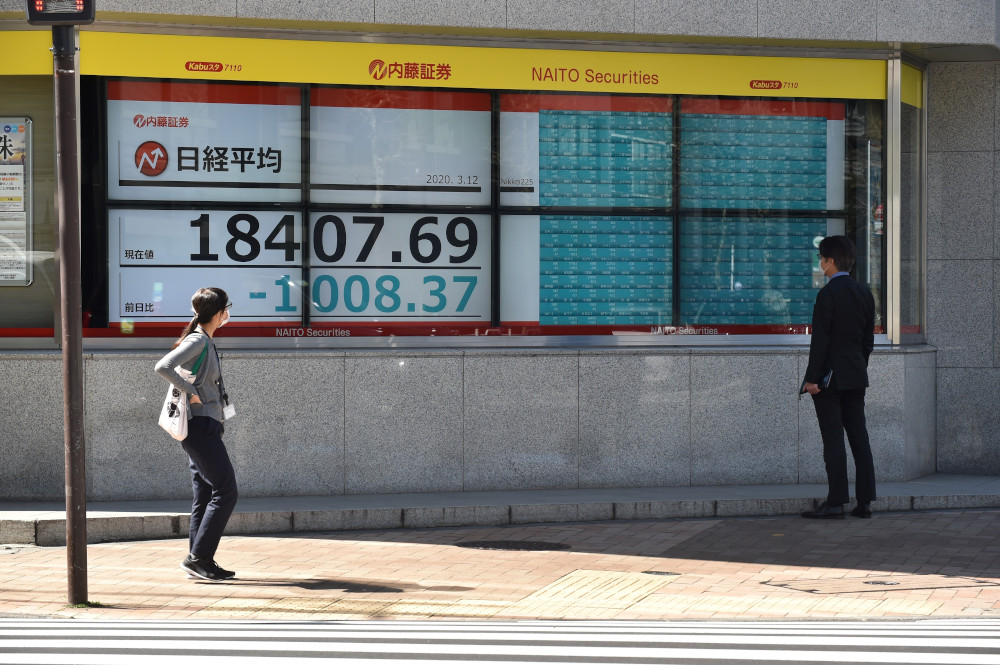 Pedestrians look at a quotation board displaying the share price numbers on the Tokyo Stock Exchange in Tokyo March 12, 2020. u00e2u20acu201d AFP pic 