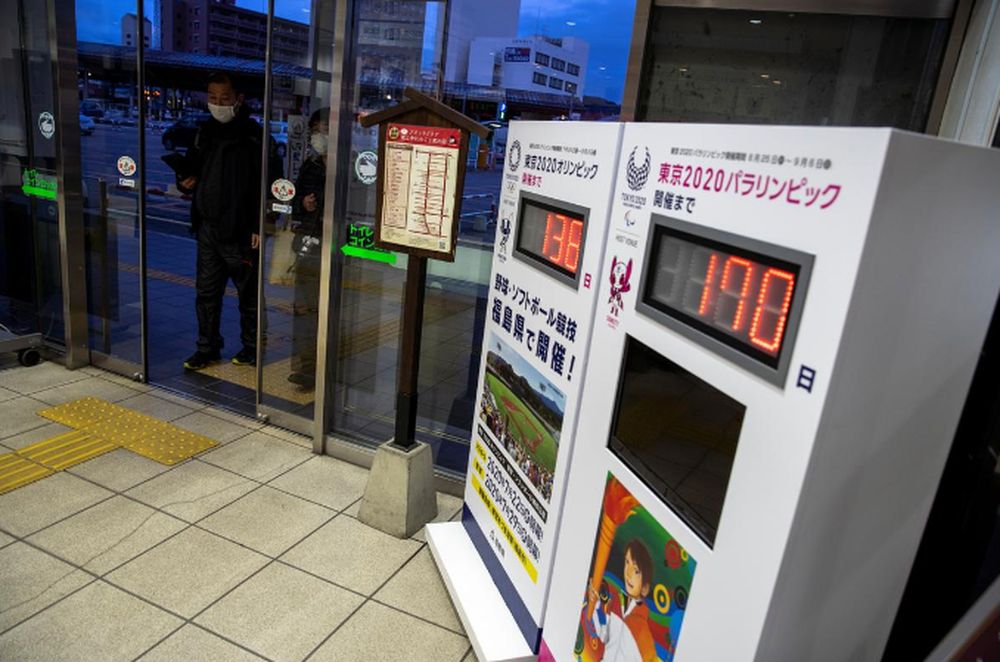 Men wearing protective face masks, following an outbreak of COVID-19 walk past countdown clocks for the opening ceremony of the Tokyo 2020 Olympic in Aizu-Wakamatsu, Fukushima prefecture, Japan, March 8, 2020. u00e2u20acu201d Reuters pic