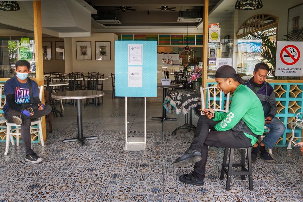 GrabFood riders wait to pick up their orders at an eatery  in Taman Tun Dr Ismail March 18, 2020. — Picture by Ahmad Zamzahuri