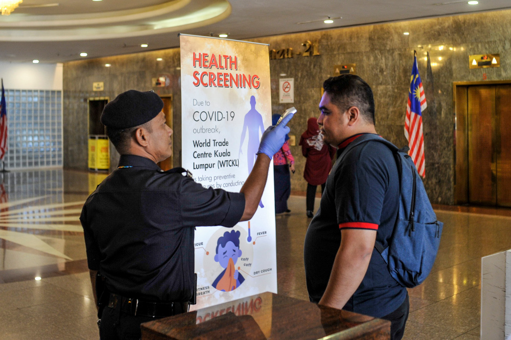 Workers are seen scanning the body temperature of visitors at Putra World Trade Center in Kuala Lumpur, March 12, 2020. u00e2u20acu201d Picture by Shafwan Zaidon