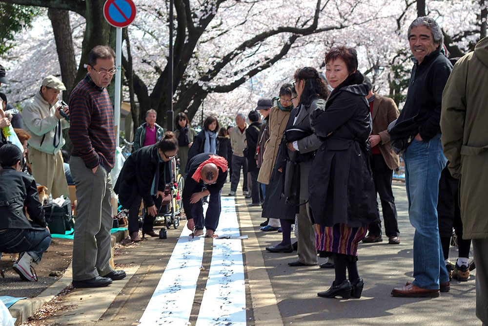 Sosuke Kimura, the acclaimed Japanese calligrapher painting beneath the cherry trees.