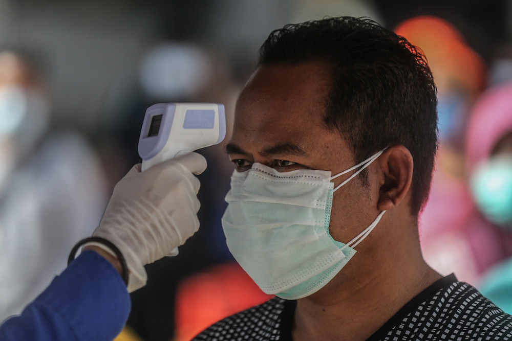 Members of the Malaysian Civil Defence Force check the temperature of shoppers at Chow Kit market during the movement control order (MCO) in Kuala Lumpur April 5, 2020. u00e2u20acu201d Picture by Firdaus Latif