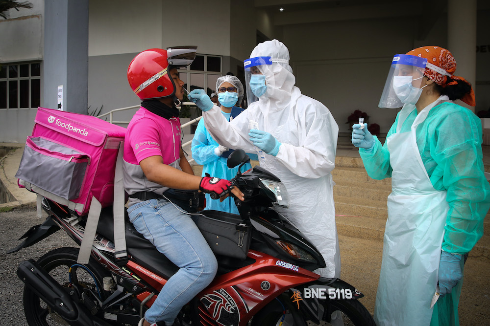 Health workers take coronavirus test samples of a food delivery rider at a drive-thru Covid-19 testing centre in Shah Alam April 18, 2020. u00e2u20acu201d Picture by Yusof Mat Isa 
