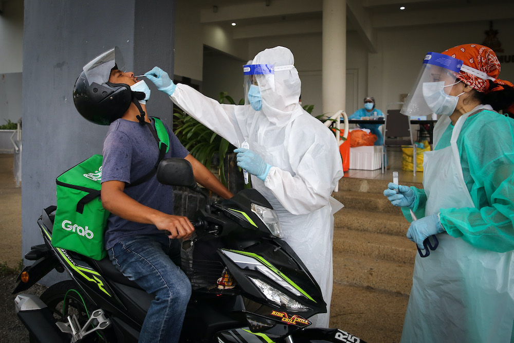 Health workers take coronavirus test samples of a food delivery rider at a drive-thru Covid-19 testing centre in Shah Alam April 18, 2020. u00e2u20acu201d Picture by Yusof Mat Isa 