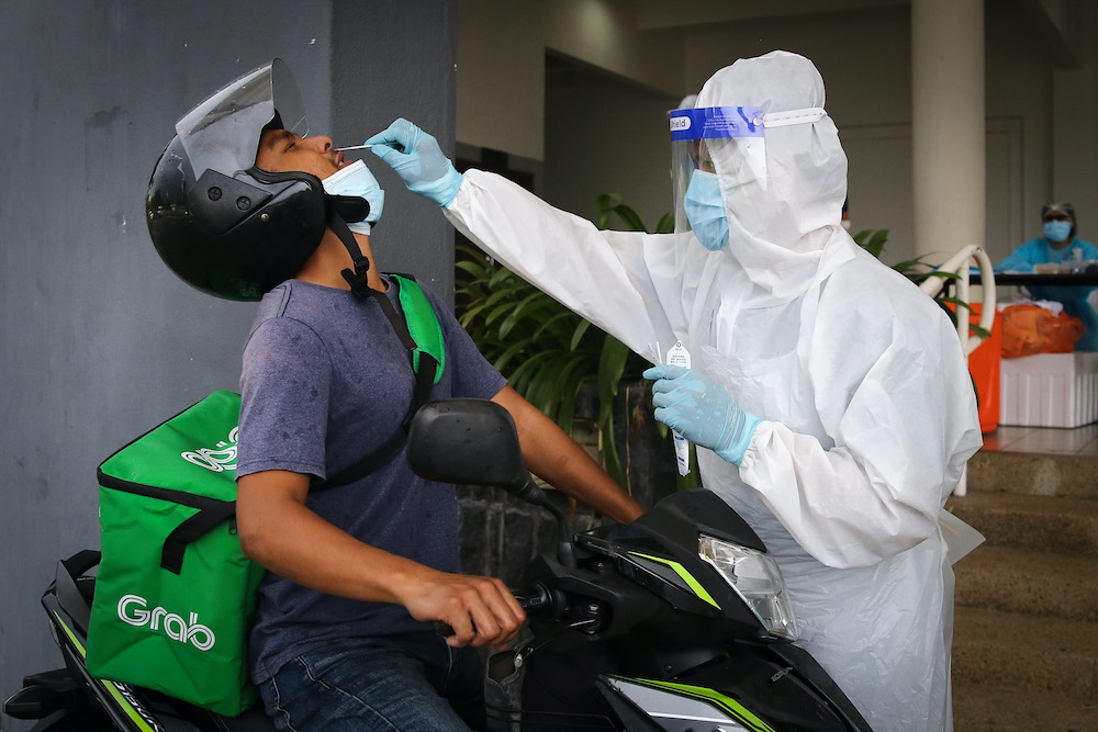 Health workers take coronavirus test samples of a food delivery rider at a drive-thru Covid-19 testing centre in Shah Alam April 18, 2020. u00e2u20acu201d Picture by Yusof Mat Isa 