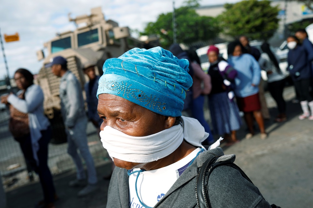 An elderly woman covers her face with a makeshift mask as people queue to collect social grants and shop during a 21-day nationwide lockdown in Khayelitsha township near Cape Town March 31, 2020. u00e2u20acu201d Reuters pic