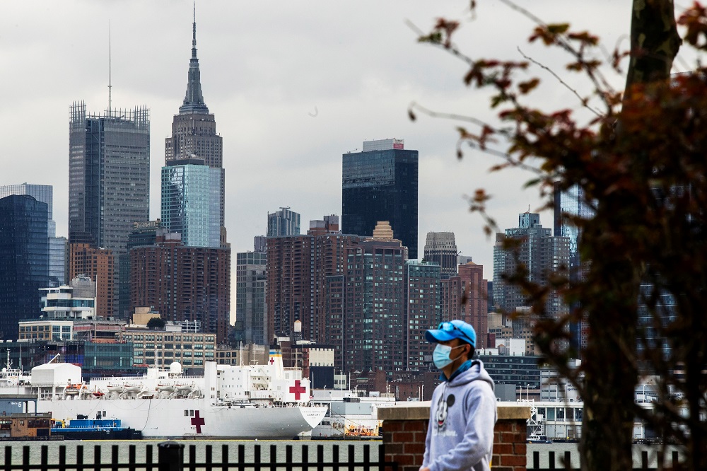 A man wears a face mask while the USNS Comfort and the Empire State Building are seen from Weehawken, New Jersey, during the outbreak of the coronavirus disease in New York March 31, 2020. — Reuters pic