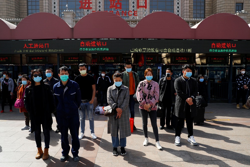 People wearing face masks stand to pay tribute as China holds national mourning for those who died of the coronavirus disease (Covid-19), on the Qingming tomb-sweeping festival, in Beijing April 4, 2020. — Reuters pic