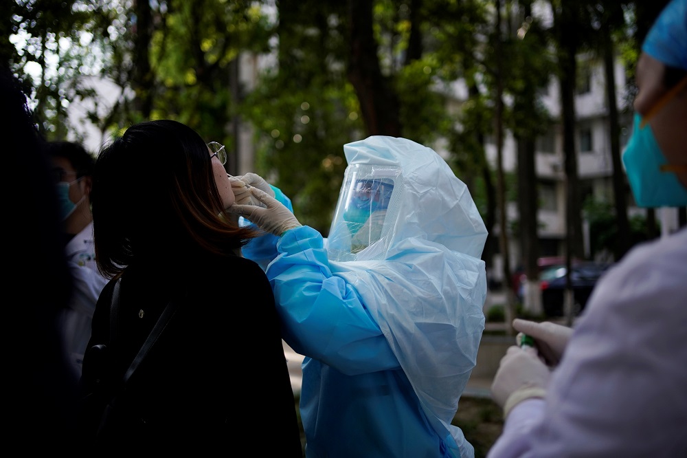 A woman receives a nucleic acid test for Covid-19 on a street near a hospital after the lockdown was lifted in Wuhan April 13, 2020. u00e2u20acu201d Reuters pic