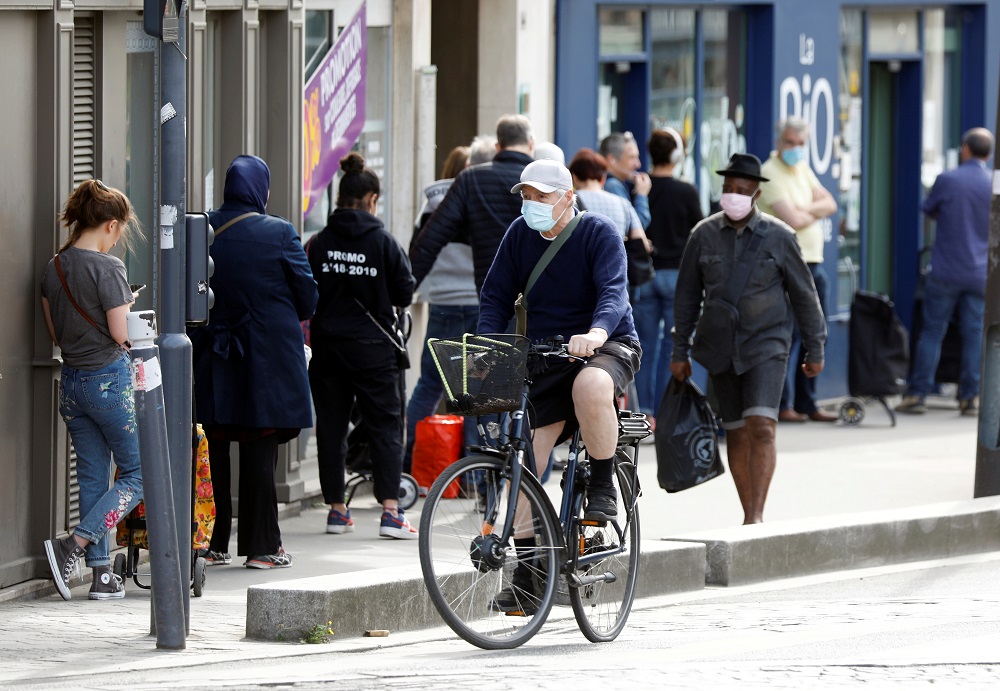 A man, wearing a protective face mask, rides past people queuing outside a Biocoop grocery in Fontenay-sous-Bois as the spread of the coronavirus disease continues in France, April 20, 2020. u00e2u20acu201d Reuters pic