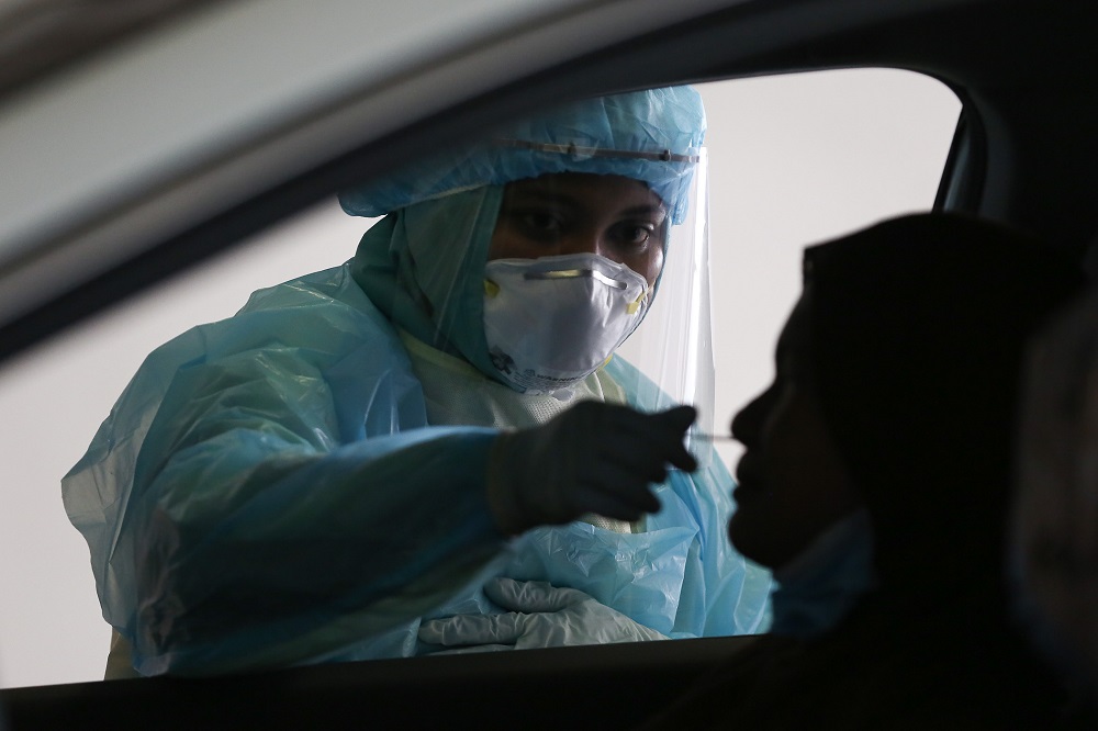 A health worker in protective suit collects swab samples from a motorist at a drive-through testing site for Covid-19 at MSU Medical Centre in Shah Alam April 10, 2020. u00e2u20acu201d  Picture by Yusof Mat Isa