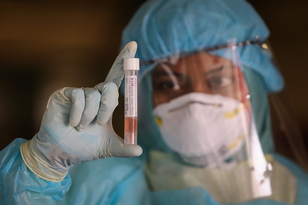 A health worker looks at a sample collected from a motorist at a drive-through testing site for Covid-19 at MSU Medical Centre in Shah Alam April 10, 2020. u00e2u20acu201d  Picture by Yusof Mat Isa