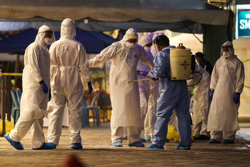 Health workers are seen disinfecting themselves after screening Selangor Mansion residents for Covid-19 in Kuala Lumpur April 11, 2020. — Picture by Yusof Mat Isa