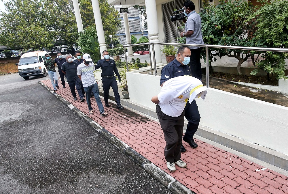 The three men who defied the movement control order by playing golf are led in handcuffs to the Magistrate Court in Batu Gajah April 17, 2020. u00e2u20acu201d Picture by Farhan Najib