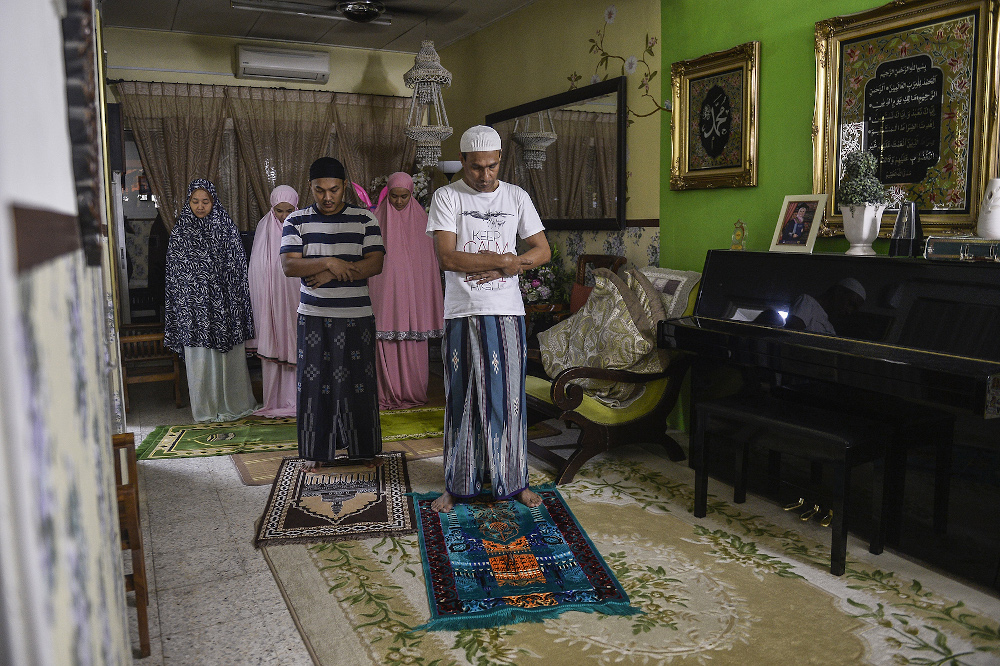A family performs tarawih prayer at home a day before Ramadan during movement control order (MCO) in Puchong April 23, 2020. — Picture by Miera Zulyana 