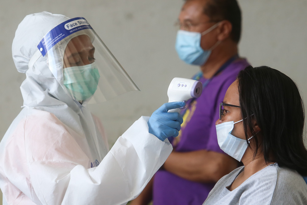 People queuing to enter the Chow Kit wet market must have their temperature checked, wear a mask and sanitise their hands before they are allowed in April 24, 2020. u00e2u20acu201d Picture by Choo Choy May