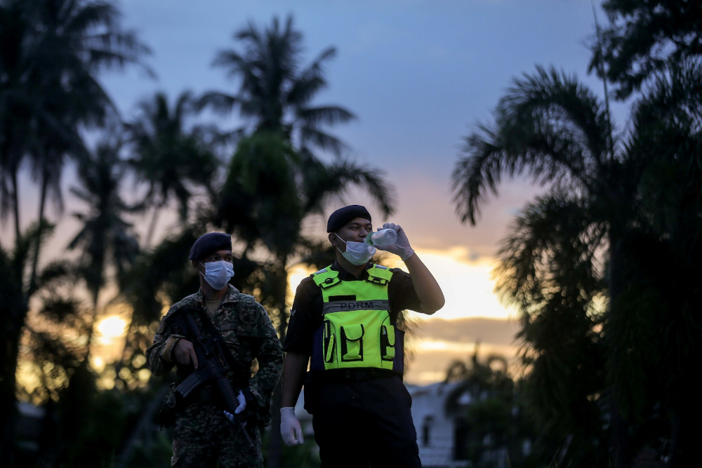 Police and army personnel who were carrying out their duties during movement control order (MCO) break their fast and praying at a roadblock in Ipoh April 24, 2020. u00e2u20acu201d Picture by Farhan Najib 