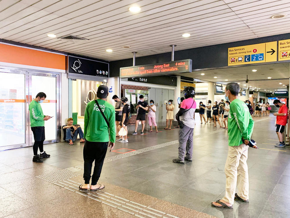 Delivery riders waiting and customers queueing for bubble tea from Koi at Yew Tee MRT Station on April 21, 2020 at about 9pm. — TODAY pic