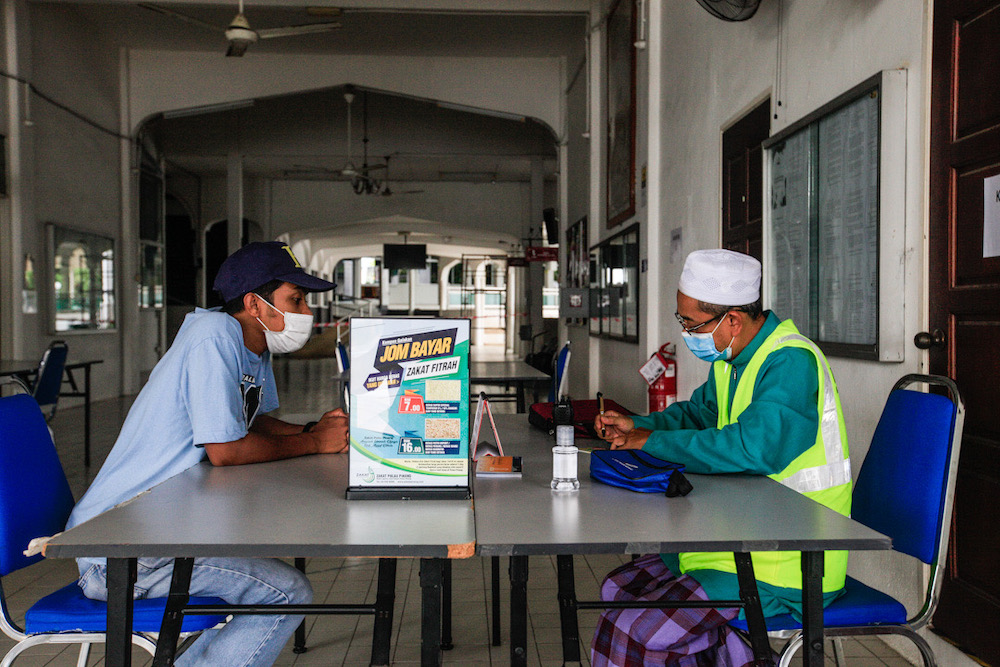 A man pays his zakat fee to the Amil or the zakat collector at Masjid Jamek Seberang Jaya, April 30, 2020. u00e2u20acu201d Picture by Sayuti Zainudin
