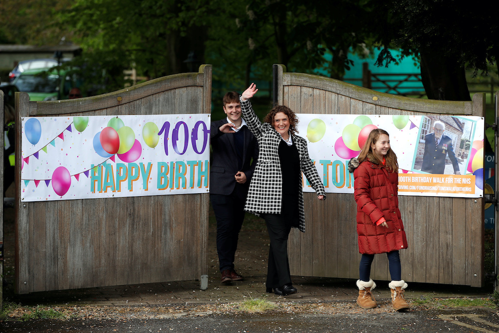 The family of army veteran Captain Tom Moore, daughter Hannah Ingram-Moore and Grandchildren Benji and Georgia wave outside his home on his 100th birthday, following the outbreak of the coronavirus disease in Marston Moretaine, Britain, April 30, 2020. �