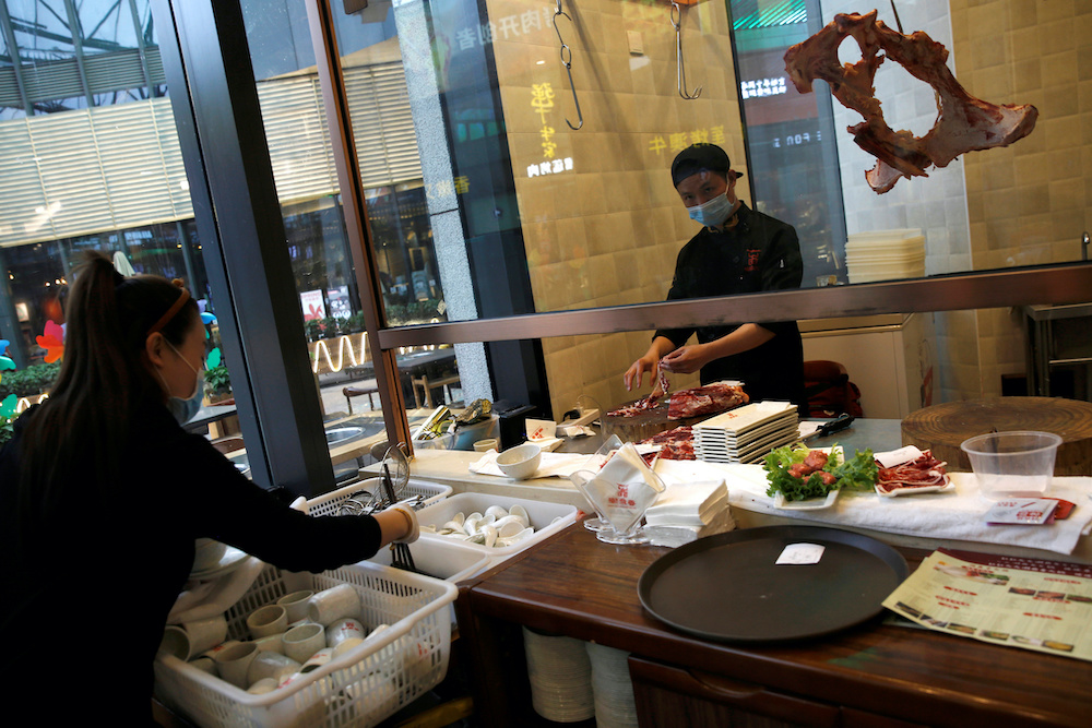 A chef wearing a face mask prepares beef as a waitress sorts tableware at a beef hotpot restaurant in Beijing, amid an outbreak of the novel coronavirus disease (Covid-19) in the country, China April 7, 2020. u00e2u20acu201d Reuters picnn