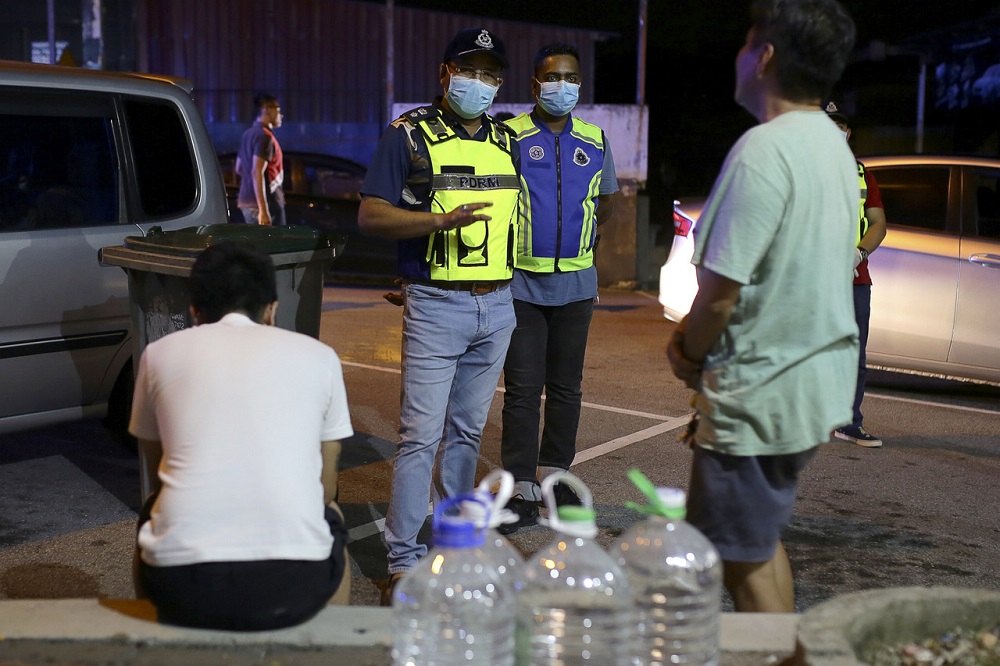 Nilai district police chief Mohd Nor Marzukee Besar (centre) speaks to a few men caught loitering outdoors during the movement control order in Nilai April 10, 2020. u00e2u20acu201d Bernama pic