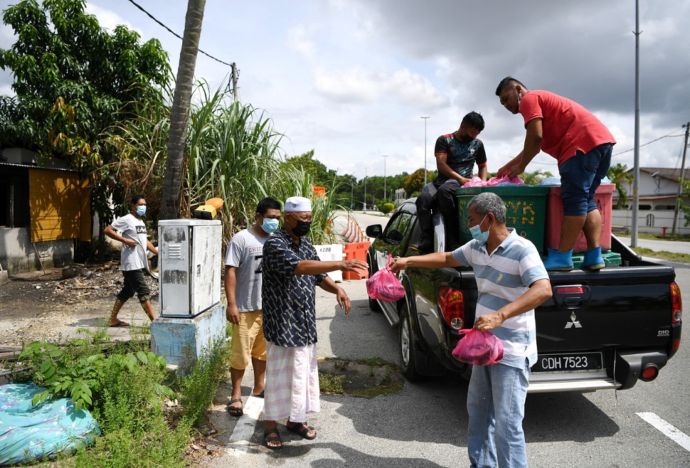 Spokesperson for the group of fishing boat owners, Abdul Rahim Abdul Rahman (second right), distributing the fish to residents of Kampung Tanah Putih in Kuantan April 13, 2020. u00e2u20acu201d Bernama pic