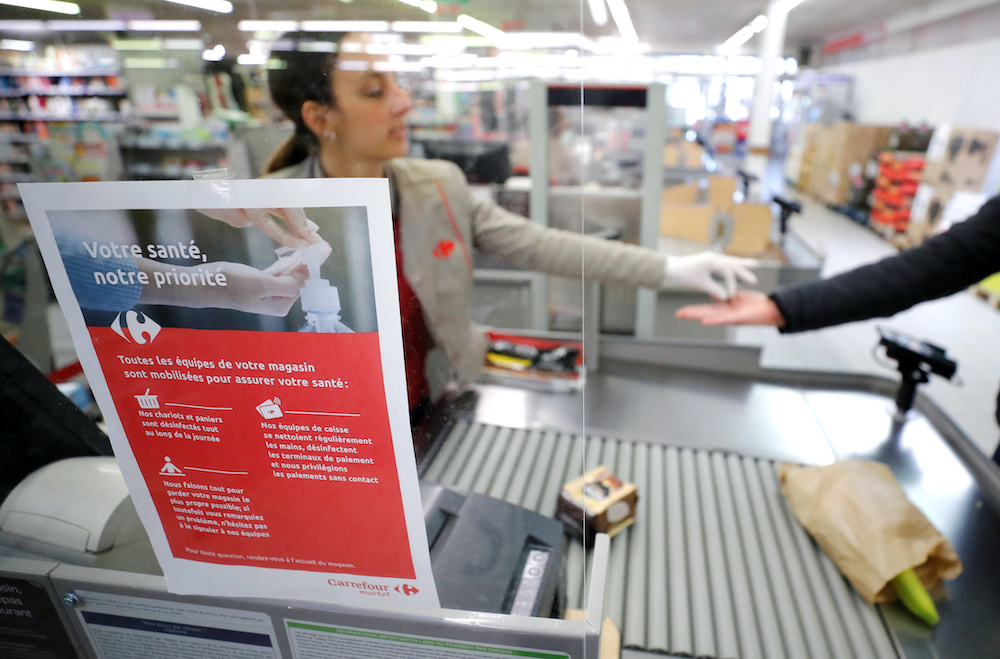 A cashier serves a customer behind a plastic protection shield at a supermarket in Coueron near Nantes, as the spread of the coronavirus disease (Covid-19) continues in France, March 30, 2020.u00e2u20acu201d Reuters pic