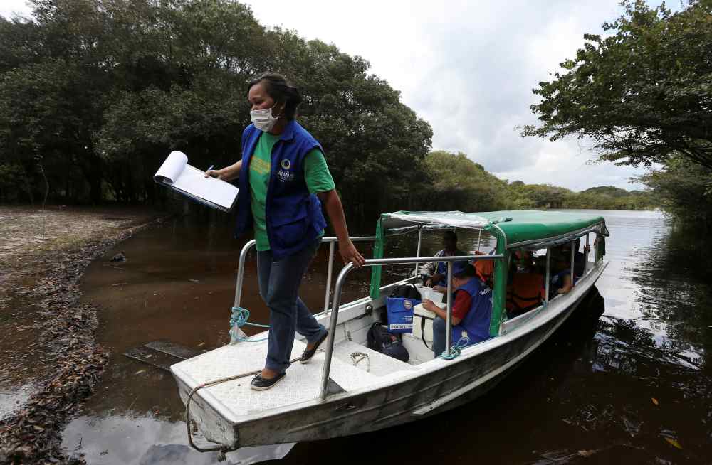 Health agents are seen in a boat before the vaccination of Ribeirinhos (forest dwellers) against flu and H1N1, as advised by health officials to facilitate diagnosis for coronavirus, amid the Covid-19 outbreak, along the Negro River banks, in Manaus, Braz