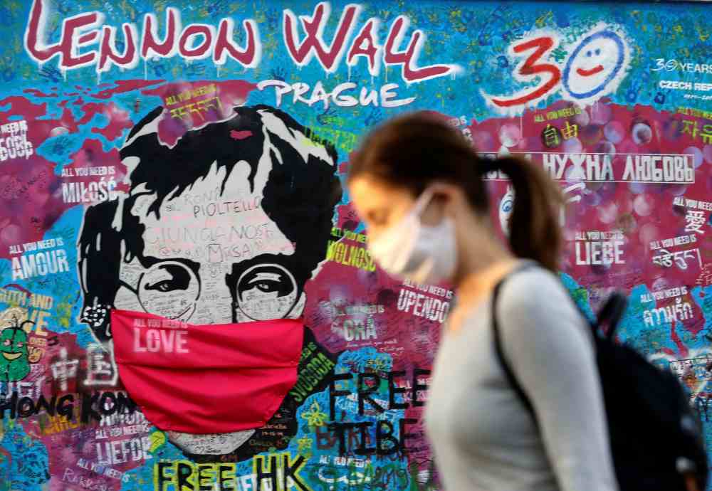 A woman wearing a face mask walks past the legendary graffiti-covered John Lennon Wall as the spread of the coronavirus disease continues in Prague April 6, 2020. u00e2u20acu2022 Reuters pic 