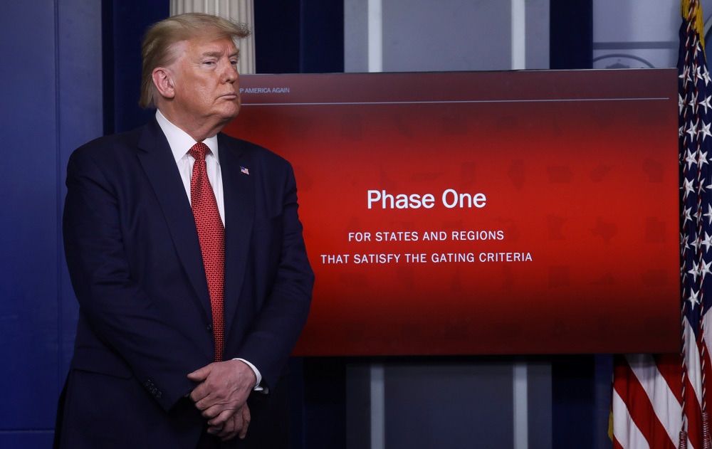 US President Donald Trump stands in front of a slide on a video monitor debuting u00e2u20acu02dcPhase Oneu00e2u20acu2122 of his administration's plans for u00e2u20acu02dcOpening Up America Againu00e2u20acu2122 during the daily coronavirus task force briefing at the White House in Washington April 16, 2