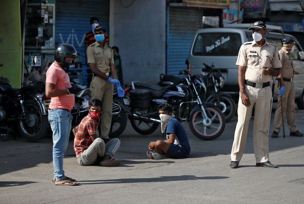 Two men are ordered by the police to sit on a road, as part of a punishment for breaking the nationwide lockdown in India to slow the spread of Covid-19, in Dharavi, one of Asiau00e2u20acu2122s largest slums, during the coronavirus disease outbreak, in Mumbai, India,