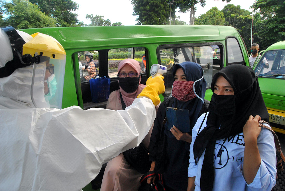 Passengers wearing face masks have temperature checked by a healthcare worker amid the spread of coronavirus disease (Covid-19) outbreak, on an intersection of the road in Bogor, West Java province, Indonesia, April 8, 2020 in this photo taken by Antara F