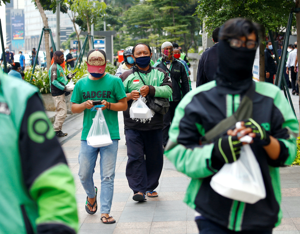 Online motorbike taxi drivers hold boxes of meals as people queue for free food given by a company amid spread of the coronavirus disease in Jakarta, Indonesia April 17, 2020n. u00e2u20acu201d  Reuters picnn
