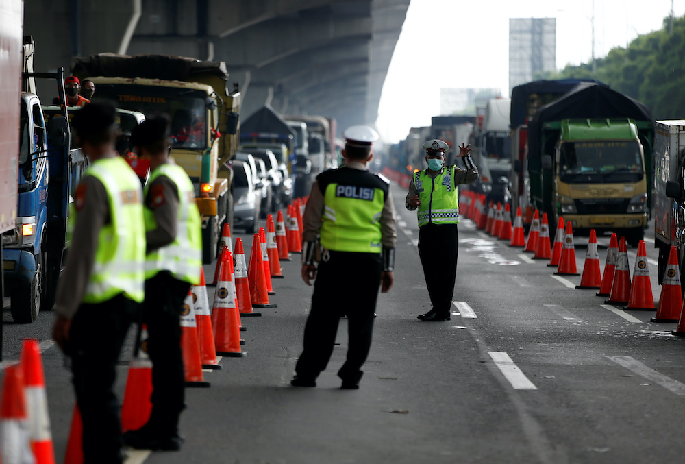 A police officer wearing a protective face mask gestures towards a colleague as they guard a highway checkpoint in Bekasi, on the outskirts of Jakarta, Indonesia, April 24, 2020. u00e2u20acu201d Reuters pic