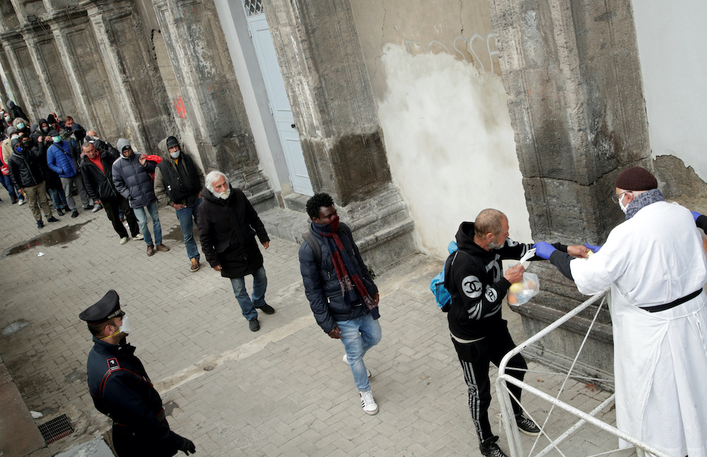 Priest Francesco wearing a face mask and protective gloves, hands out bags of food to homeless and poor people, as the spread of coronavirus disease (Covid-19) continues, in Naples,Italy, March 27, 2020. u00e2u20acu201d Reuters picnnn